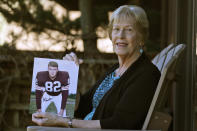 Donna Houston holds up a photograph of her husband, Jim, during his playing years with the Cleveland Browns, Friday, April 3, 2020, in Sagamore Hills, Ohio. Houston's widow would keep notes on her husband's deteriorating condition in a three-ring binder so she would be prepared for the day when he needed full-time care. (AP Photo/Tony Dejak)