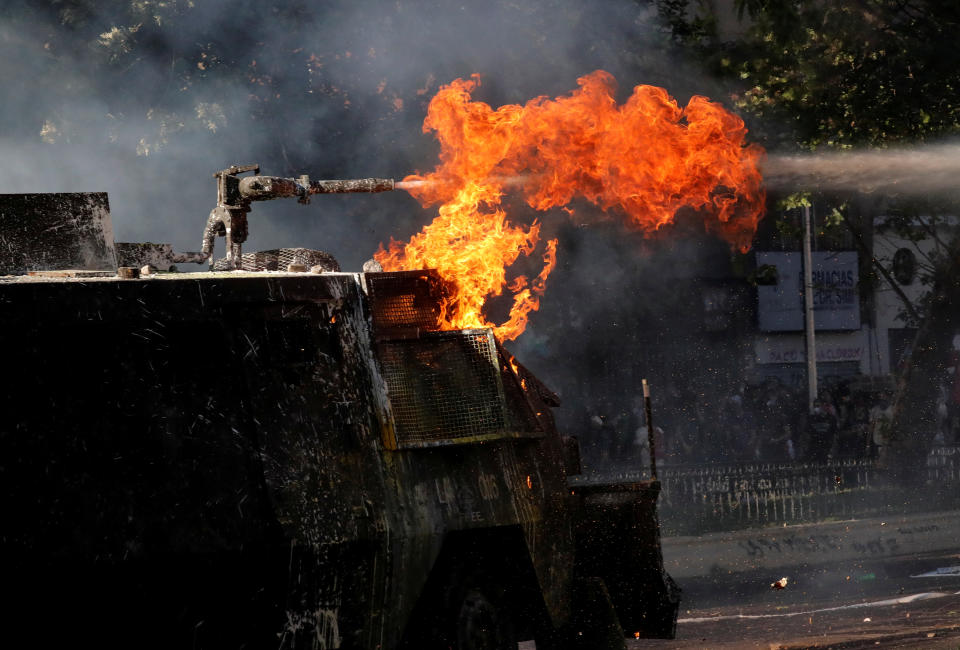 A riot police vehicle with flames uses its water cannon during an anti-government protests in Santiago, Chile on Oct. 28, 2019. (Photo: Henry Romero/Reuters)