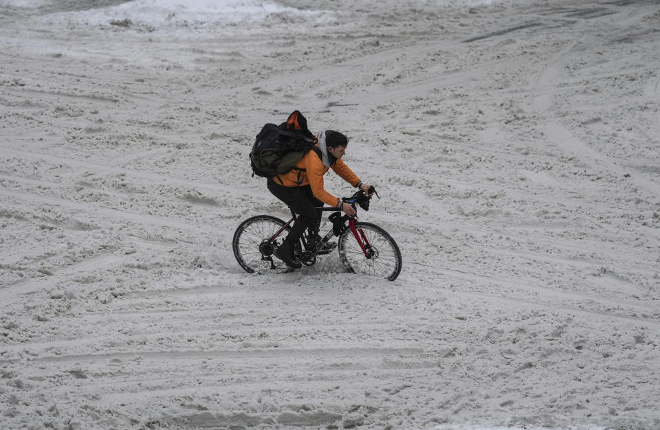 A cyclist navigates through the snow on an unplowed Robson Street as freezing rain falls in downtown Vancouver, British Columbia, Canada, on Friday, Dec. 23, 2022. (Darryl Dyck/The Canadian Press via AP)