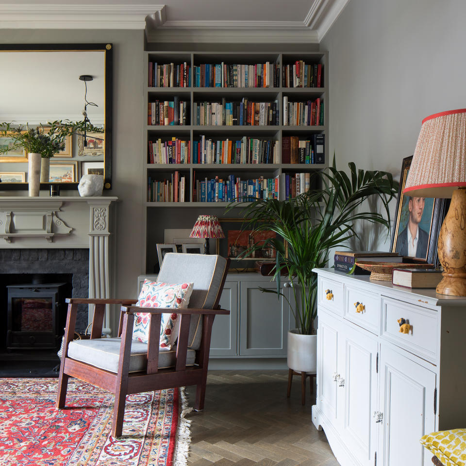 living room. with armchair by fireplace, book shelves and patterned Turkish rug