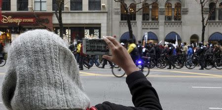 A tourist shopping on Michigan Avenue shoots video of protesters marching down Chicago's Michigan Avenue during a protest march against police violence in Chicago, Illinois December 24, 2015. REUTERS/Frank Polich