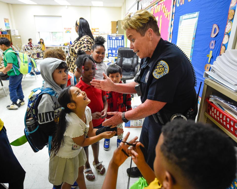 Metro Nashville police officer Faye Okert does a "secret" handshake with a student at Stratton Elementary School in Madison, Tenn. on Wednesday, May 25, 2022. Okert has worked as a school resource officer in Metro Nashville Public Schools for 15 years.