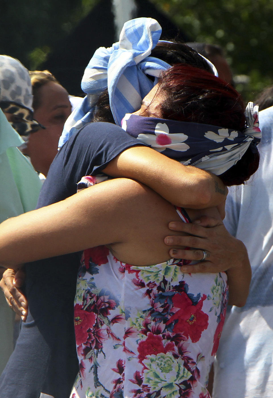Women who cover their faces so as not to be identifiable by the press and police embrace outside Anisio Jobim Prison Complex after a deadly riot erupted among inmates in Manaus in the northern state of Amazonas, Brazil, Sunday, May 26, 2019. A statement from the state prison secretary says prisoners began fighting among themselves around noon Sunday, and security reinforcements were rushed to complex. (AP Photo/Edmar Barros)