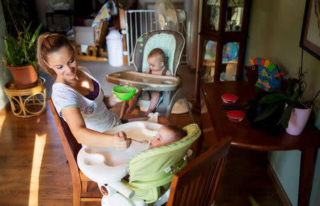 Heather Padgett feeds her daughters Kinsley and Kiley at her home in Cincinnati, Ohio July 16, 2015. REUTERS/Aaron P. Bernstein