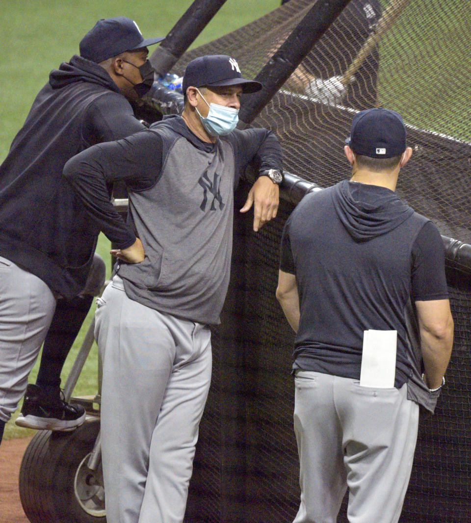 New York Yankees Manager Aaron Boone, center, watches batting practice before a baseball game against the Tampa Bay Rays Tuesday, May 11, 2021, in St. Petersburg, Fla. New York announced two hours before first pitch that third base coach Phil Nevin, who is fully vaccinated, is under quarantine away from the team after a positive COVID-19 test. (AP Photo/Steve Nesius)