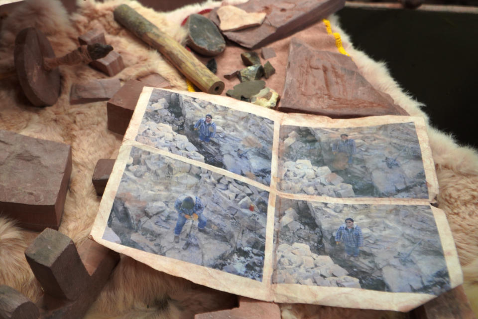 Mark Pederson "Swift Horse," a member of the Sisseton-Wahpeton Dakota Nation and a fourth generation quarrier, shows old photographs of himself digging at his family's quarry at the Pipestone National Monument Museum on Wednesday, May 3, 2023, in Pipestone, Minn. (AP Photo/Jessie Wardarski)