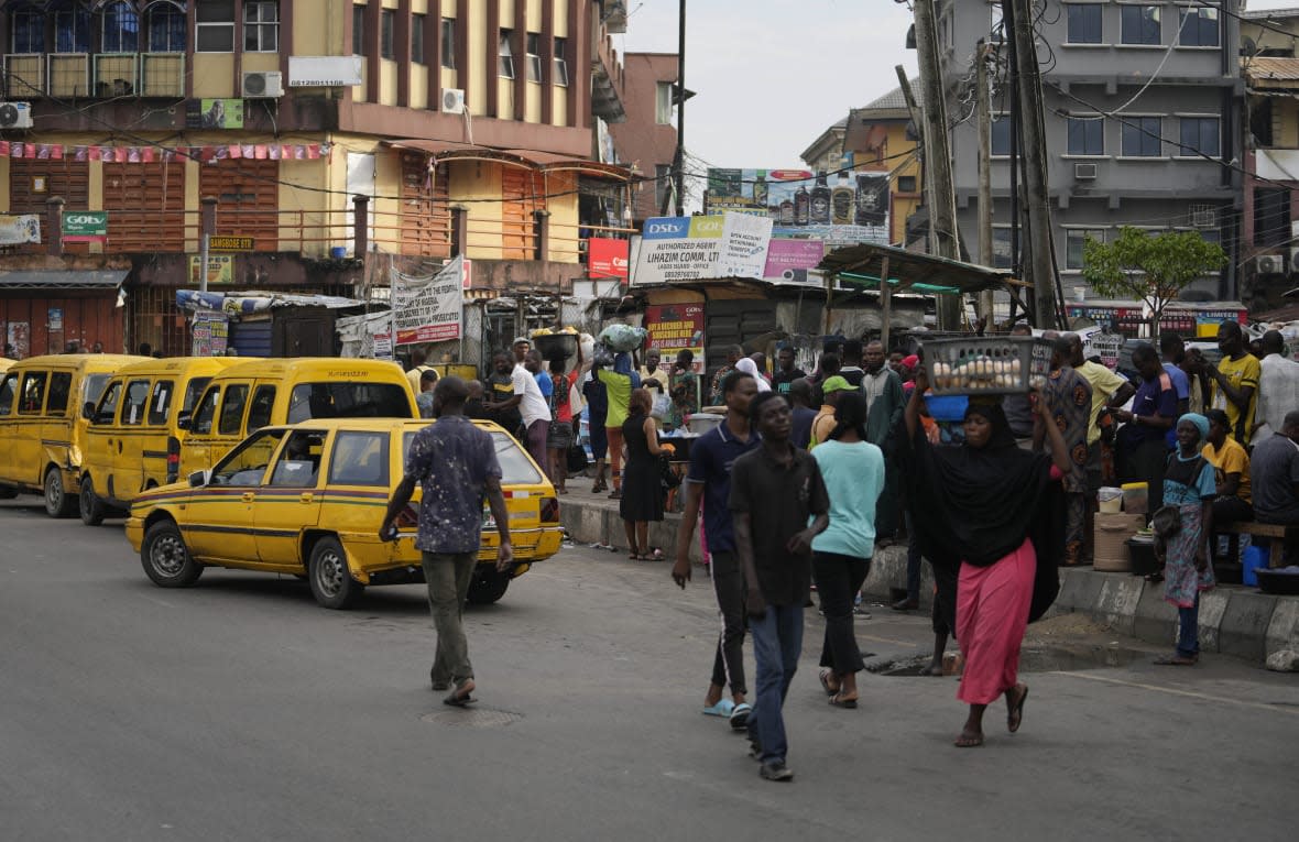 People walk on the street in Lagos, Nigeria, Wednesday, March 1, 2023. (AP Photo/Sunday Alamba)