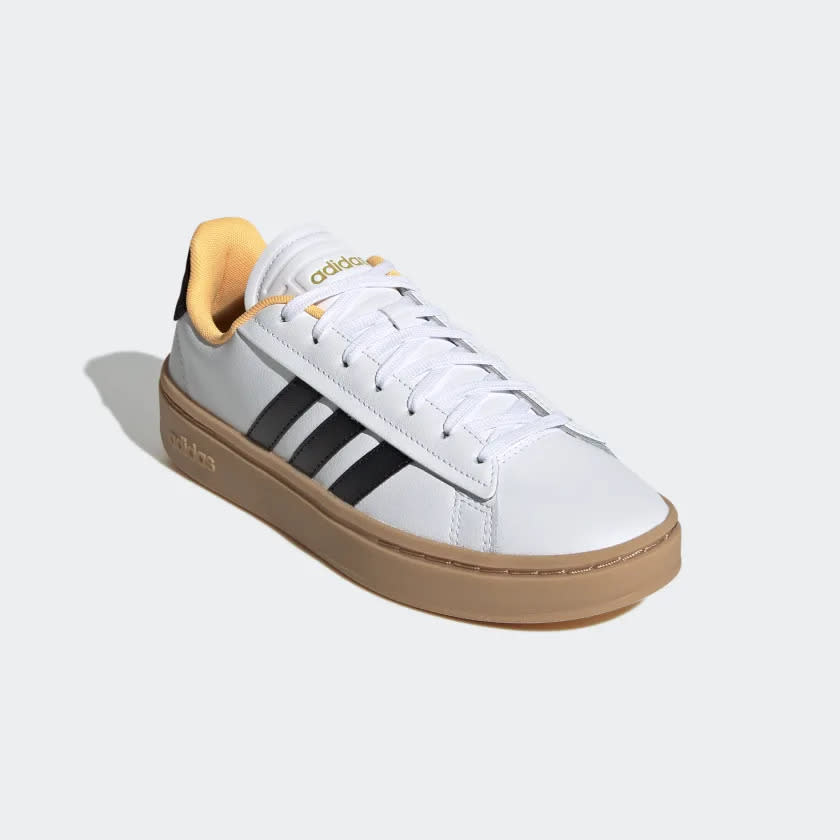 White sneaker with black three stripes and tan sole.