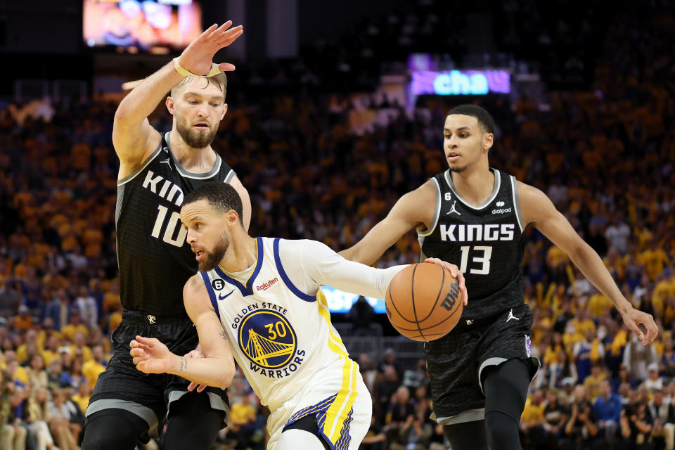 Golden State Warriors star Stephen Curry is guarded by Domantas Sabonis and Keegan Murray of the Sacramento Kings during Game 4 of their first-round NBA playoffs series at Chase Center in San Francisco on April 23, 2023. (Ezra Shaw/Getty Images)