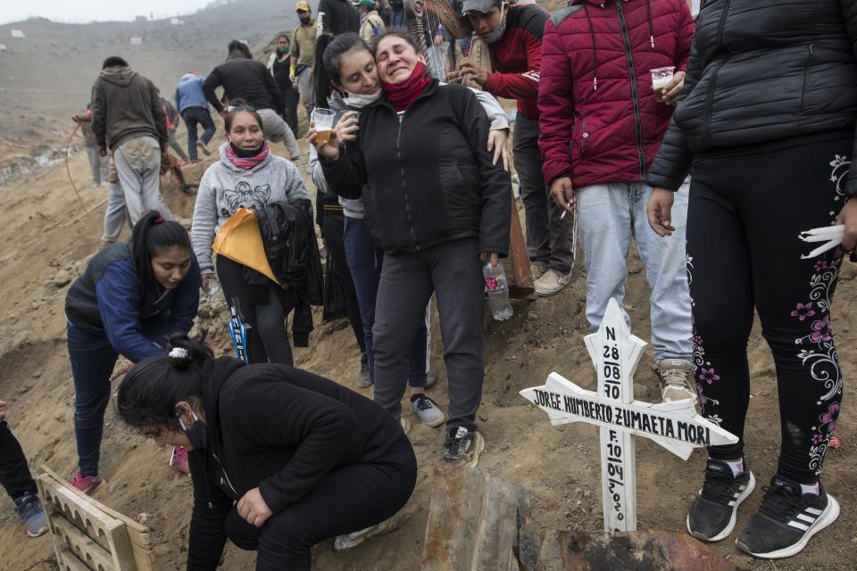 Gregoria Zumaeta, 44, center, mourns the death of her brothers Jorge Zumaeta, 50, and Miguel Zumaeta, 54, who died from COVID-19, at the Nueva Esperanza cemetery on the outskirts of Lima, Peru, Tuesday, May 26, 2020. (AP Photo/Rodrigo Abd)
