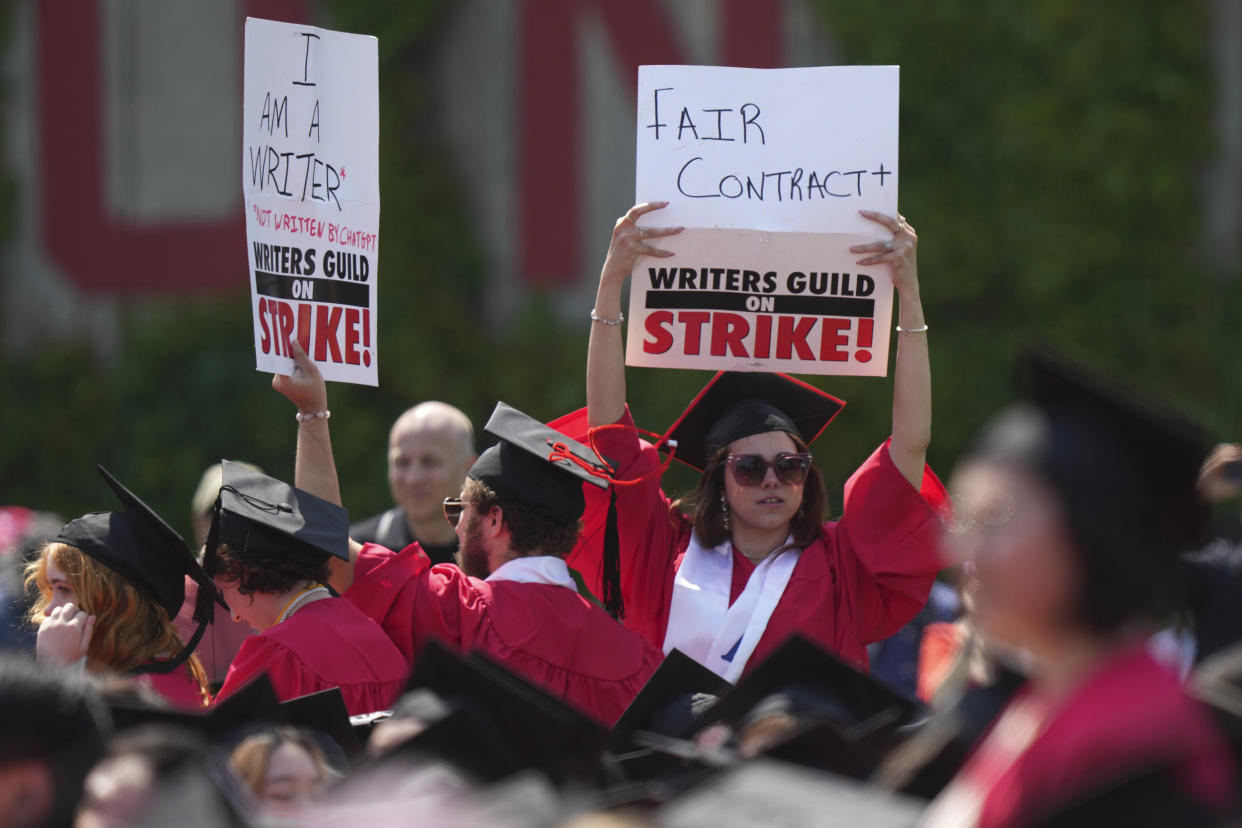 Graduating students hold signs in support of the Hollywood writers' strike during David Zaslav's commencement address (Steven Senne / AP)