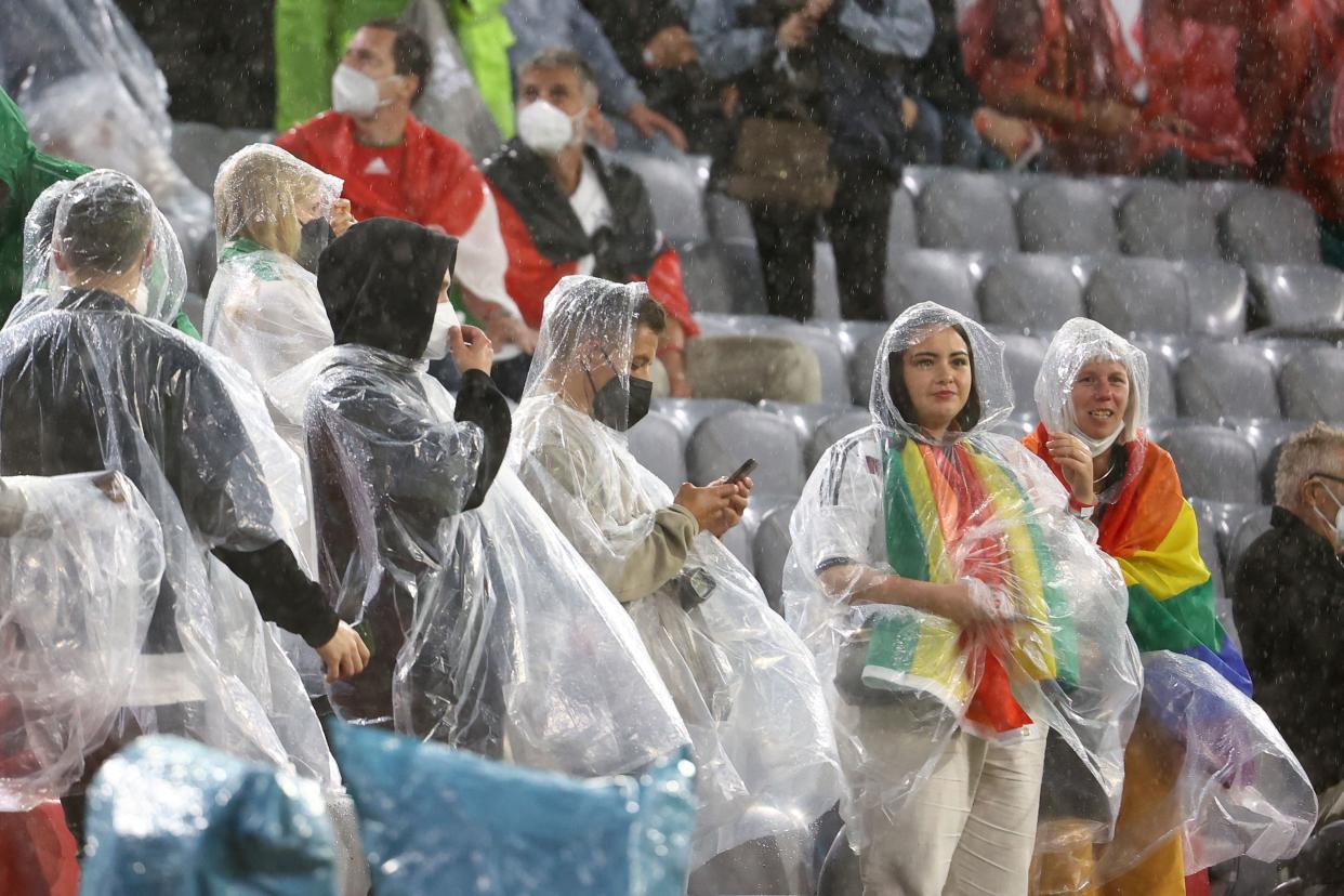 Germany fans, some wearing rainbow flags, shelter from the rain in ponchos prior to the UEFA EURO 2020 Group F football match between Germany and Hungary at the Allianz Arena in Munich on June 23, 2021. (Photo by KAI PFAFFENBACH / POOL / AFP) (Photo by KAI PFAFFENBACH/POOL/AFP via Getty Images)