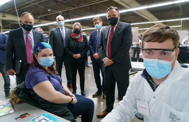 Quebec Premier François Legault and Health Minister Christian Dubé watch a woman register for her COVID-19 vaccine at a clinic in Montreal's Olympic Stadium 