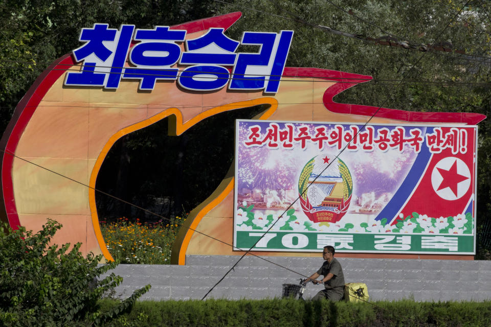 A North Korean man cycles past propaganda prepared ahead of the 70th anniversary of North Korea's founding day in Pyongyang, North Korea, Friday, Sept. 7, 2018. North Korea will be staging a major military parade, huge rallies and reviving its iconic mass games on Sunday to mark its 70th anniversary as a nation. (AP Photo/Ng Han Guan)