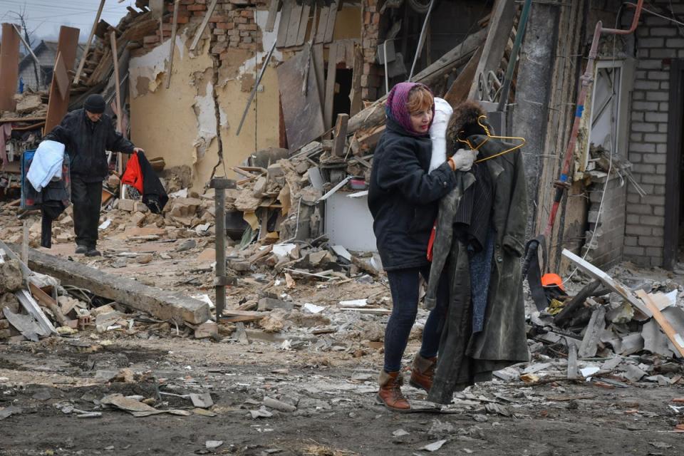 Zaporizhzhia residents carry their belongings as they leave homes devastated in Saturday’s rocket attacks (AP)