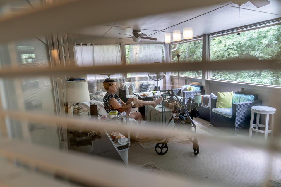 Janet Paulsen pulls her injured leg up with her arms while resting at her home in Acworth, Ga., Monday, Aug. 7, 2023. Her medical care has since cost about $2.5 million, much of it borne by society at large through health insurance payments. (AP Photo/David Goldman)