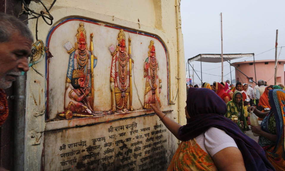 A Hindu pilgrim touches in obeisance an image of Hindu deities Rama, Sita and Lakshman in Ayodhya, India , Saturday, Nov. 9, 2019. India's security forces were on high alert ahead of the Supreme Court's verdict Saturday in a decades-old land title dispute between Muslims and Hindus over plans to build a Hindu temple on a site where Hindu hard-liners demolished a 16th century mosque in 1992, sparking deadly religious riots. (AP Photo/Rajesh Kumar Singh)