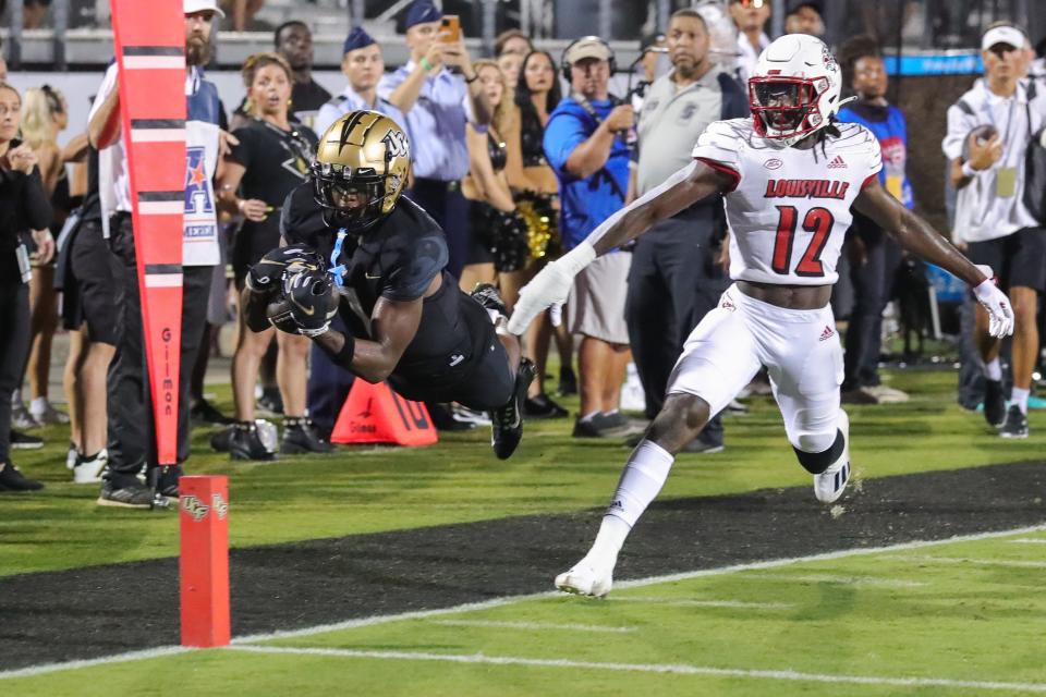 UCF wide receiver Javon Baker dives for the end zone in front of Louisville Cardinals cornerback Jarvis Brownlee.