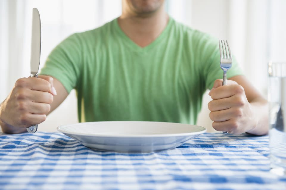 Mixed race man holding fork and knife at table