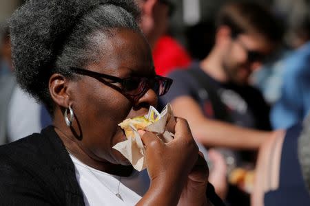 A woman eats a hot dog as she attends a celebration marking the opening of a new exhibit at Ellis Island highlighting the immigrant history behind the "Hot Dog" in New York City, U.S., June 28, 2017. REUTERS/Lucas Jackson