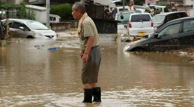 A man walks through the flood water at the site of a landslide in a residential area. Photo: Getty