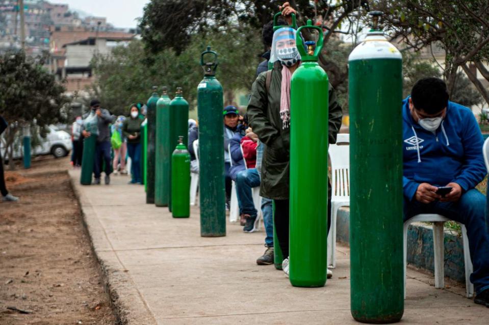 Relatives of COVID-19 patients queue to recharge oxygen cylinders. Source: AFP