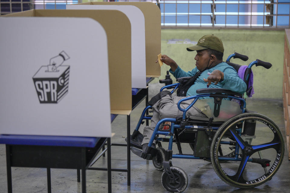 A Malaysian voter on a wheel chair casts his ballot for the state elections at a polling station in Selayang, outskirt of Kuala Lumpur, Malaysia Saturday, Aug. 12, 2023. Voting began Saturday in crucial state elections in Malaysia, where Prime Minister Anwar Ibrahim's multi-coalition government is seeking to strengthen its hold against a strong Islamic opposition. (AP Photo/Vincent Thian)