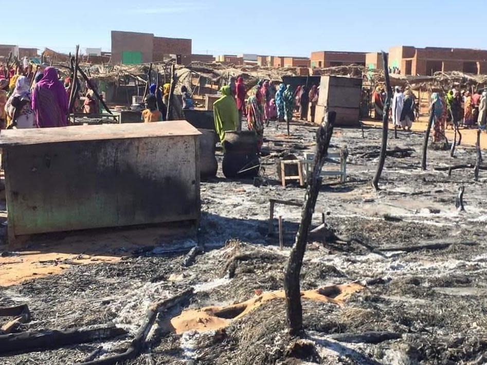 Residents of a refugee camp gather around the burned remains of makeshift structures, in Genena, Sudan: AP