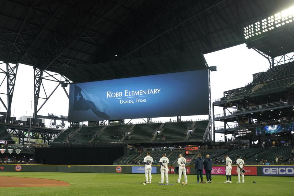 Seattle Mariners players stand on the field before their game against the Oakland Athletics at T-Mobile Park on Tuesday during a moment of silence for the victims of a shooting at Robb Elementary School in Uvalde, Texas.