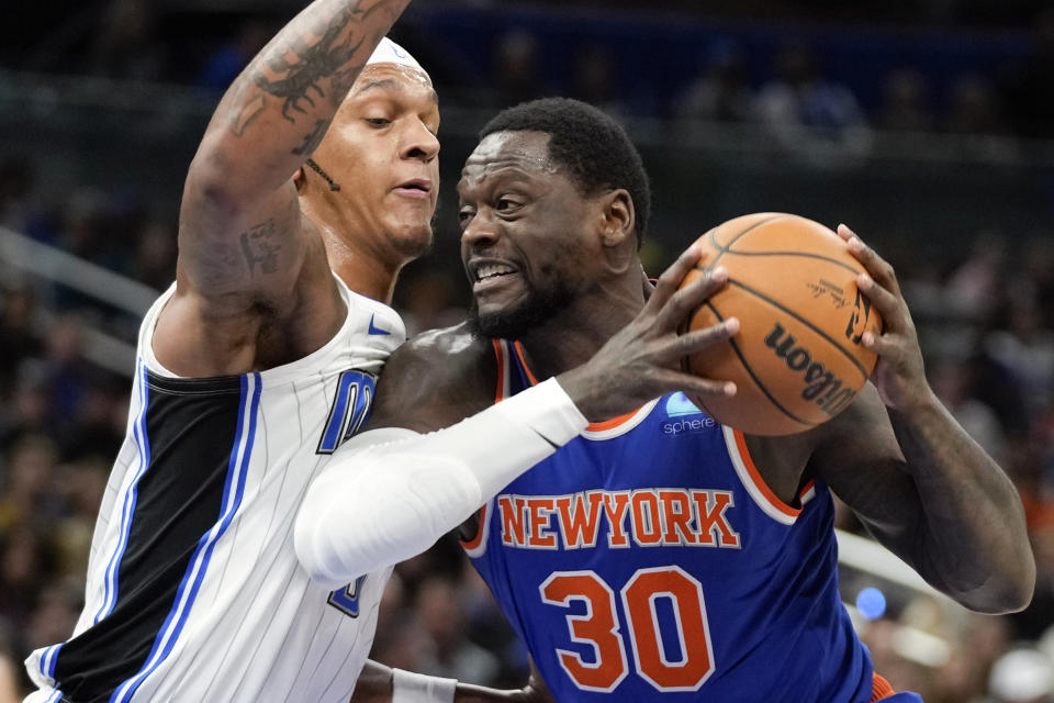 New York Knicks forward Julius Randle (30) goes to the basket for a shot against Orlando Magic forward Paolo Banchero, left, during the first half of an NBA basketball game, Friday, Dec. 29, 2023, in Orlando, Fla. (AP Photo/John Raoux)