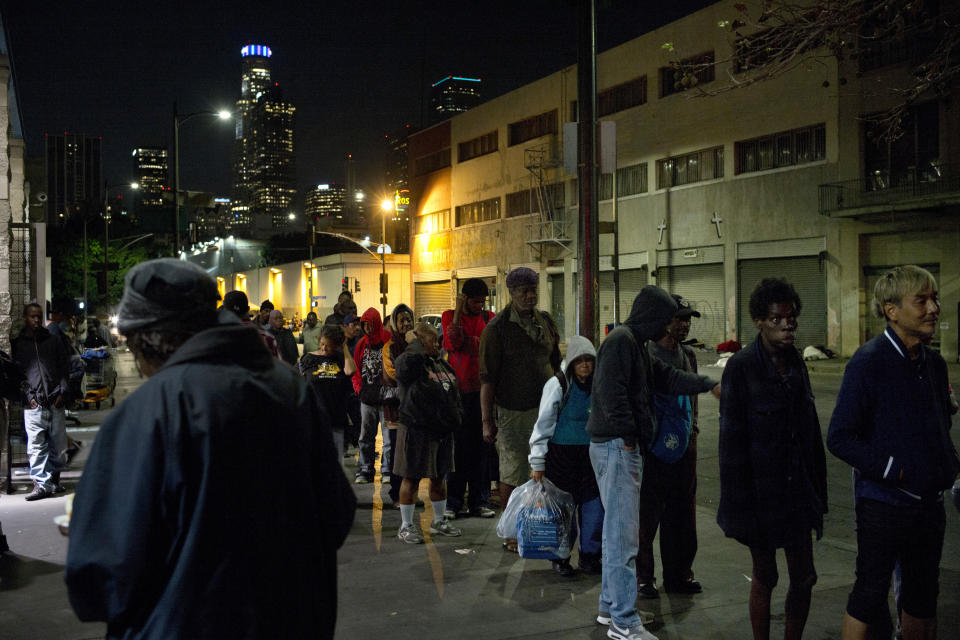 FILE - In this Sept. 19, 2017, file photo, people line up for free food being given out in an area of downtown Los Angeles known as Skid Row. Starting this week, census takers are grabbing reflective vests, face masks and flashlights and heading out at night in groups of four to track down one of the hardest populations to count in the 2020 census, the homeless. (AP Photo/Jae C. Hong,File)