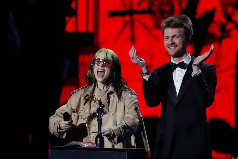 US singer-songwriter Billie Eilish (L) and her brother US artist Finneas present the award for Album of the Year during the BRIT Awards 2020 ceremony and live show in London on February 18, 2020. (Photo by Adrian DENNIS / AFP) / RESTRICTED TO EDITORIAL USE  NO POSTERS  NO MERCHANDISE NO USE IN PUBLICATIONS DEVOTED TO ARTISTS (Photo by ADRIAN DENNIS/AFP via Getty Images)