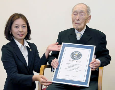 Sakari Momoi (R) receives a Guinness World Records certificate naming him as the world's oldest man at 111 years of age, in Tokyo, in this photo taken by Kyodo August 20, 2014. REUTERS/Kyodo/Files