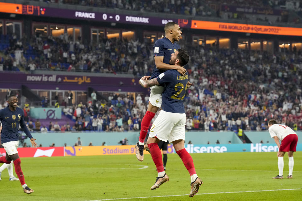 France's Kylian Mbappe celebrates with teammate Theo Hernandez after scoring his side's opening goal against Denmark during a World Cup group D soccer match at the Stadium 974 in Doha, Qatar, Saturday, Nov. 26, 2022. (AP Photo/Martin Meissner)