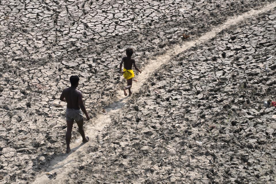 FILE - A man and a boy walk across an almost dried up bed of river Yamuna following hot weather in New Delhi, India, Monday, May 2, 2022. The U.N. weather agency reported Monday that nearly 12,000 extreme weather, climate and water-related events over much of the last half-century around the globe have killed more than 2 million people and caused economic damage of $4.3 trillion. (AP Photo/Manish Swarup, File)