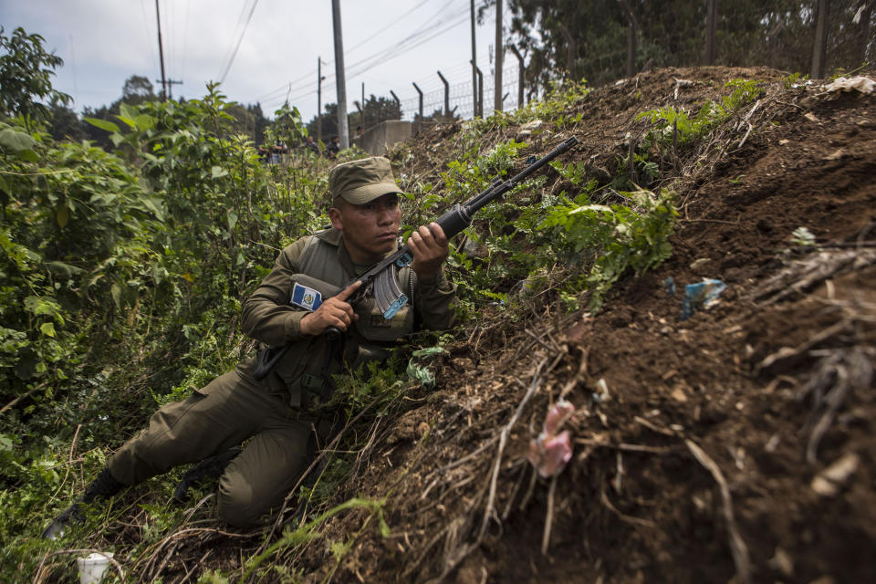 A soldier takes position outside the Pavon Rehabilitation Model Farm after a shooting inside the prison in Fraijanes, Guatemala, Tuesday, May 7, 2019. At least three people were killed and 10 people were wounded in the shooting, authorities said. (AP Photo/Oliver De Ros)