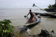 A boy loads his belongings before leaving his fishing boat in Elisha Ghat area in Bhola, Bangladesh on July 5, 2022. Mohammad Jewel and Arzu Begum were forced to flee the area last year when the river flooded and destroyed their home. (AP Photo/Mahmud Hossain Opu)