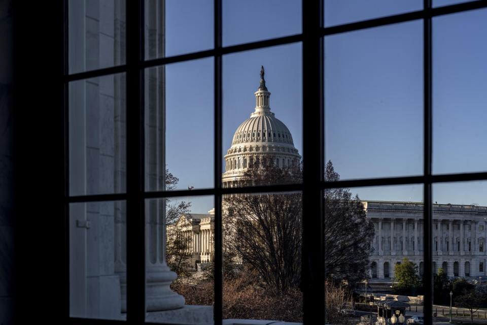 FILE - The U.S. Capitol is seen through a window in the Russell Senate Office Building in Washington, March 15, 2023. If the debt crisis now roiling Washington were eventually to send the United States crashing into recession, the repercussions of a first-ever default on the federal debt would reverberate around the world and quickly. (AP Photo/J. Scott Applewhite, File)