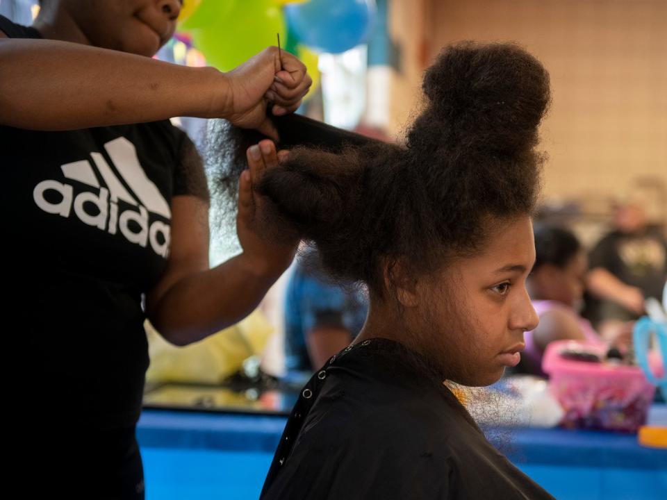 Savannah Wilborn, 13, has her hair done Saturday at the back-to-school event at Ravenna's King Kennedy Community Center.