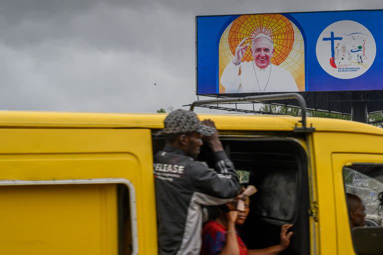 Una valla publicitaria muestra una imagen del Papa Francisco en Kinshasa el 22 de enero de 2023 mientras los pasajeros viajan en un minibús.