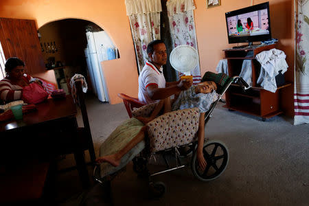 Miguel Anton (C) feeds his son Jose Gregorio Anton, 11, a neurological patient being treated with anticonvulsants, at their house in La Guaira, Venezuela February 20, 2017. REUTERS/Carlos Garcia Rawlins