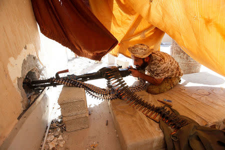 A fighter from Libyan forces allied with the U.N.-backed government aims his weapon as he takes a position on a building rooftop during a battle with Islamic State militants in Sirte, Libya September 24, 2016. REUTERS/Ismail Zitouny