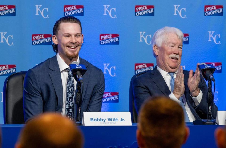 Kansas City Royals shortstop Bobby Witt Jr., left, smiles as he answers questions while the team’s owner, John Sherman, applauds during a press conference Tuesday, Feb. 6, 2024, at Kauffman Stadium in Kansas City.