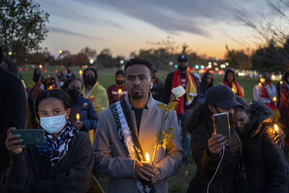 Angesom, center, holds a candle and a flower during an event in Washington on Thursday, Nov. 4, 2021, to commemorate Gebrehiwot Yemane and Haben Sahle Newfie, his two-nephews who were killed in Ethiopia Prime Minister Abiy Ahmed's administration's attacks in Tigray, the northernmost region in Ethiopia. (AP Photo/Gemunu Amarasinghe)