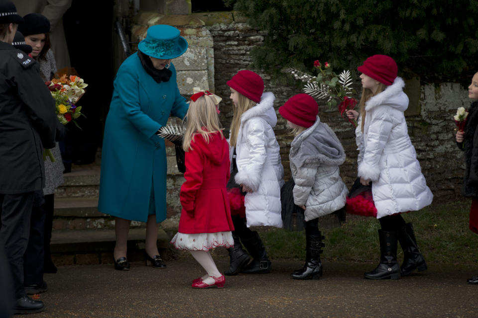 Britain's Queen Elizabeth II receives flowers from children after attending the British royal family's traditional Christmas Day church service in Sandringham, England, Tuesday, Dec. 25, 2012. (AP Photo/Matt Dunham)