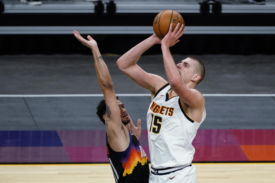 Denver Nuggets center Nikola Jokic (15) shoots over Phoenix Suns forward Abdel Nader during the first half of an NBA basketball game Saturday, Jan. 23, 2021, in Phoenix. (AP Photo/Rick Scuteri)