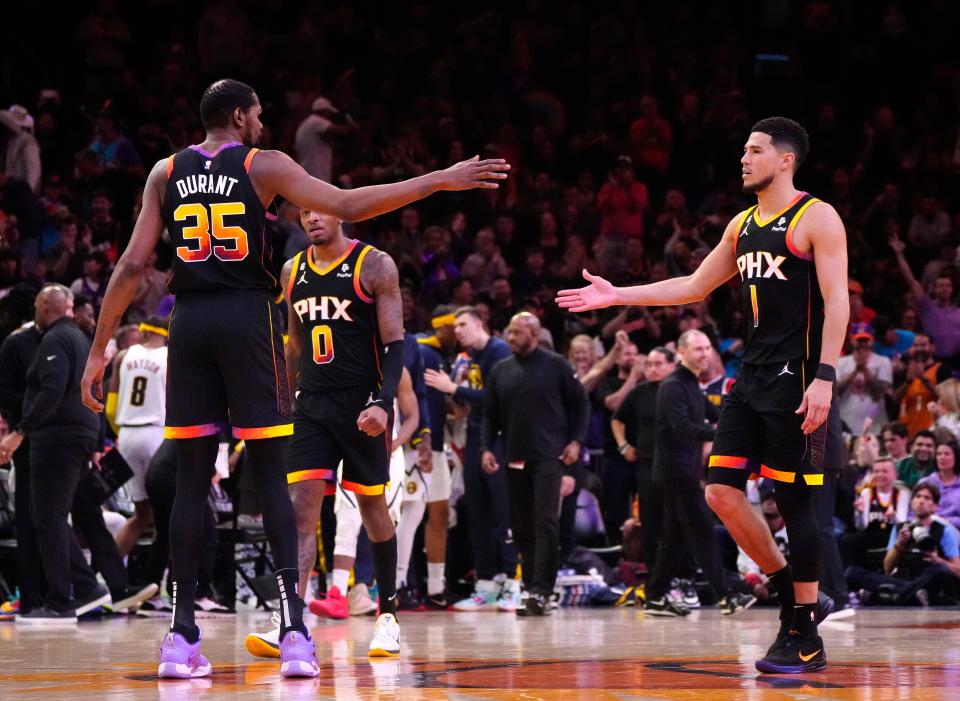 Suns forward Kevin Durant (35) high-fives guard Devin Booker (1) during a game at Footprint Center in Phoenix on April 6, 2023.