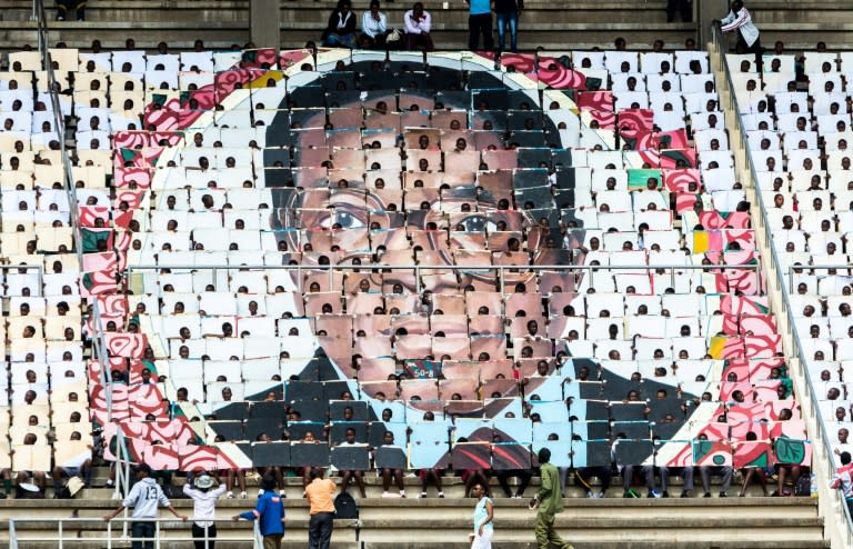 School children hold an image of Zimbabwe's President Robert Mugabe during the country's 37th Independence Day celebrations at the National Sports Stadium in Harare in April 2017