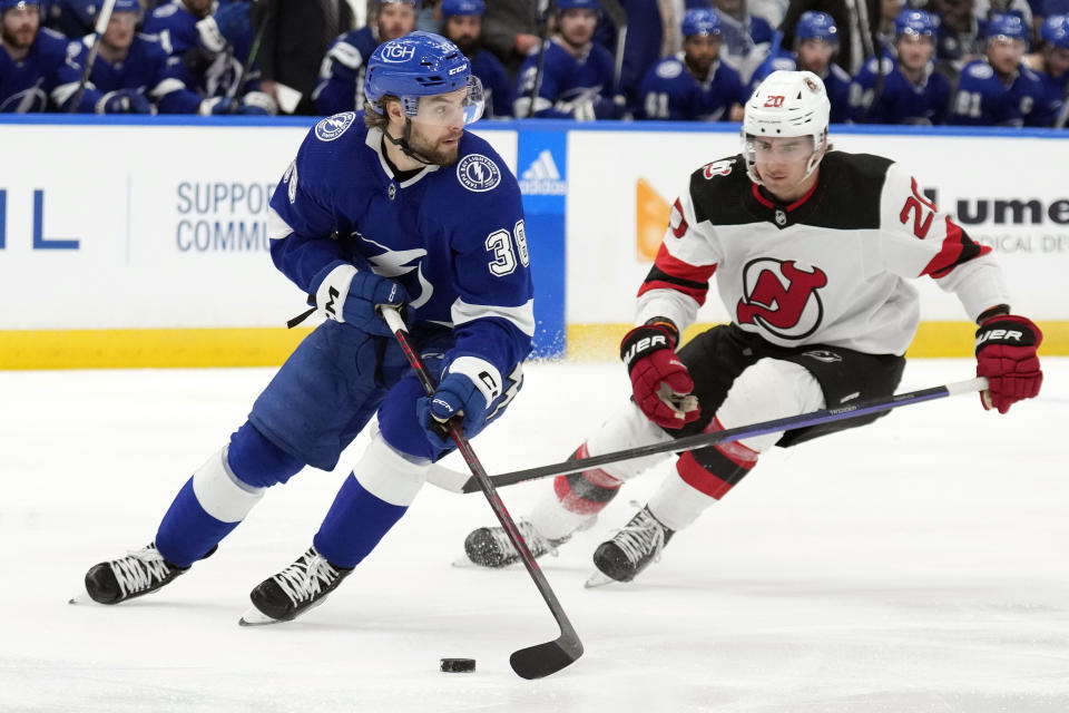 Tampa Bay Lightning left wing Brandon Hagel (38) moves the puck ahead of New Jersey Devils center Michael McLeod (20) during the first period of an NHL hockey game Sunday, March 19, 2023, in Tampa, Fla. (AP Photo/Chris O'Meara)