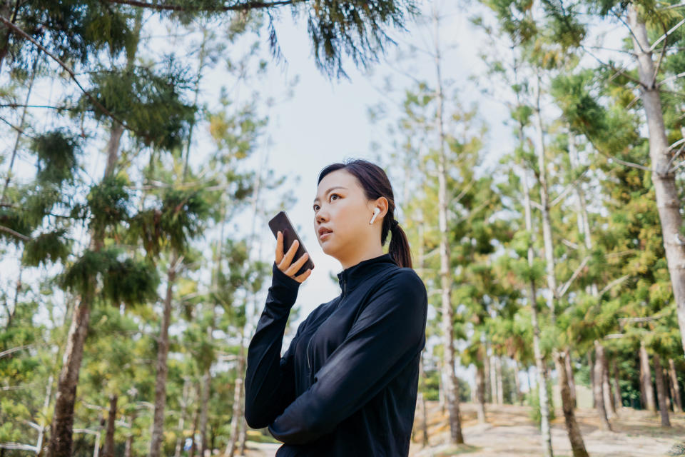 A hiker changing their outgoing voicemail in a forest